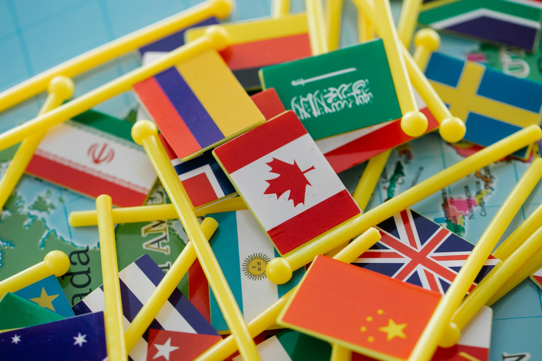 Petits drapeaux de différents pays disposés sur une carte, représentant la diversité culturelle et linguistique à travers le monde.