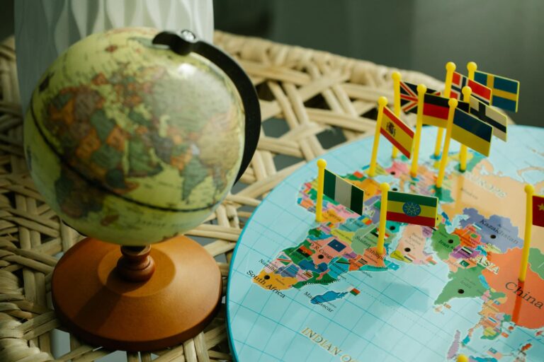 Globe terrestre miniature à côté d'une carte avec des drapeaux représentant différents pays du monde.