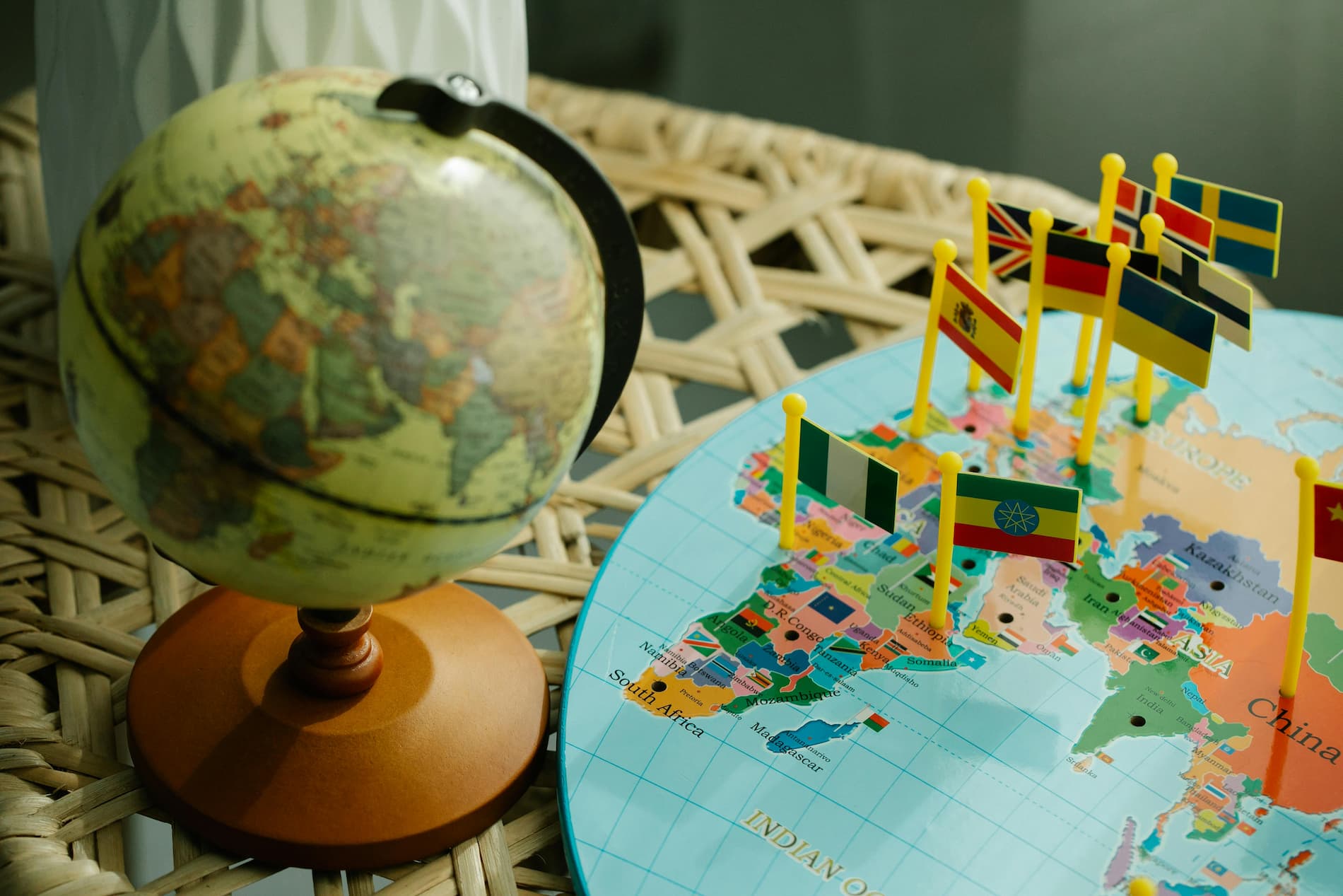 Globe terrestre miniature à côté d'une carte avec des drapeaux représentant différents pays du monde.