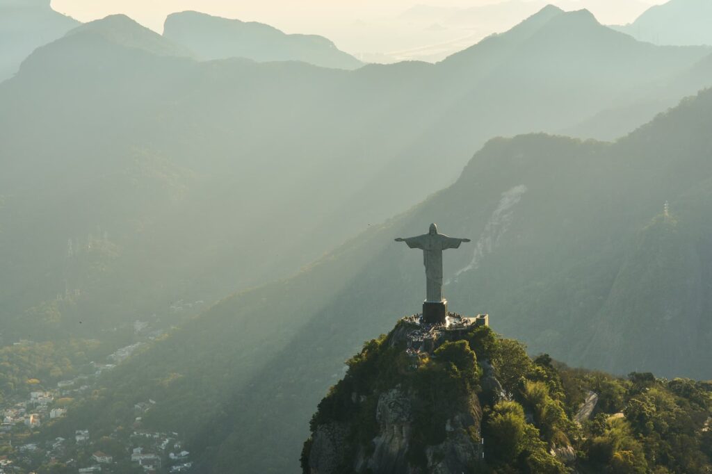 La statue du Christ Rédempteur à Rio de Janeiro, surplombant une forêt luxuriante et les montagnes environnantes sous un éclairage matinal.
