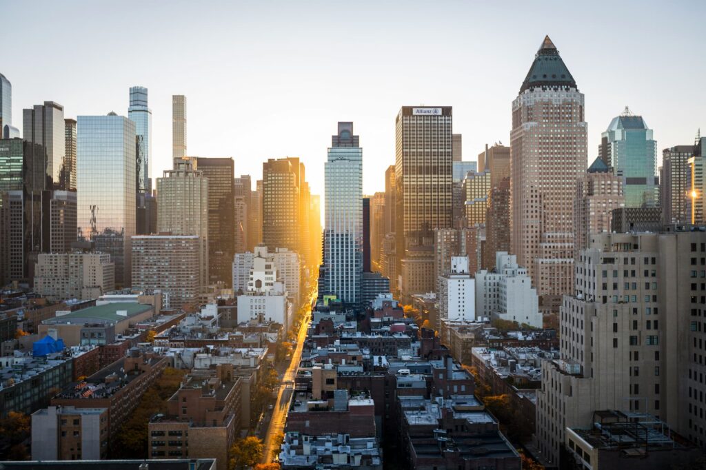Vue aérienne de la skyline de New York au lever du soleil, avec des gratte-ciels illuminés par les rayons dorés du matin.