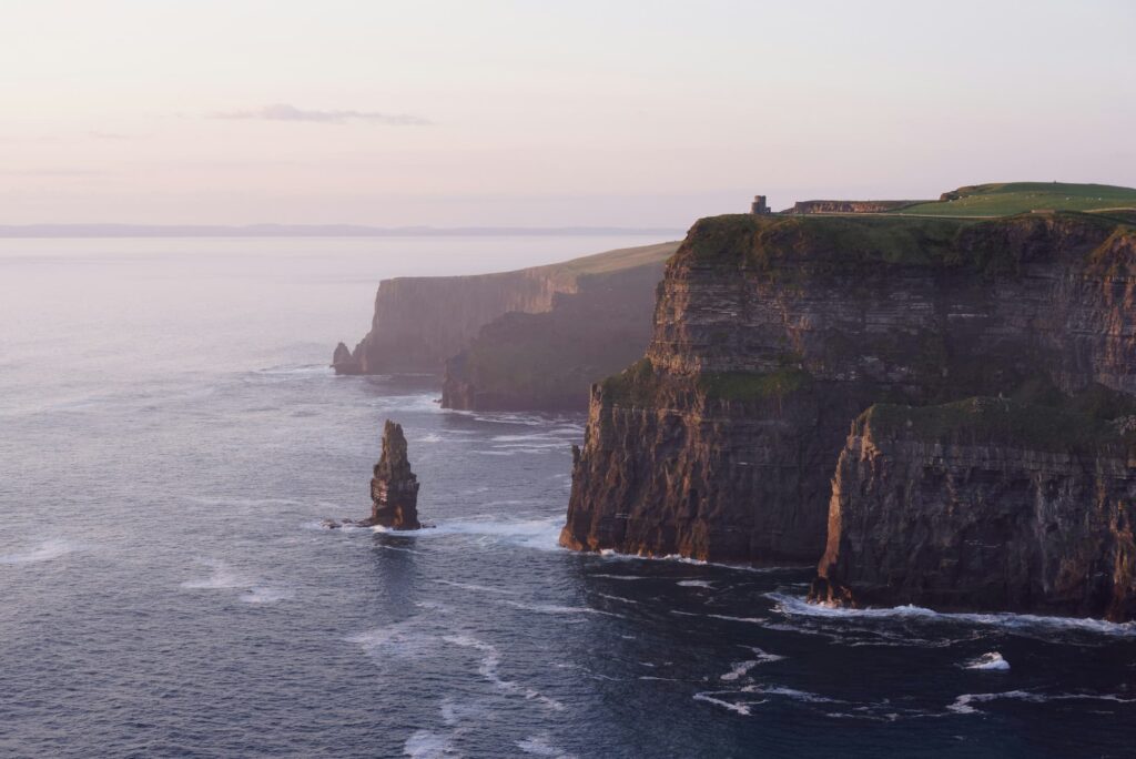 Falaises de Moher en Irlande au coucher du soleil, avec des rochers imposants surplombant l'océan Atlantique.
