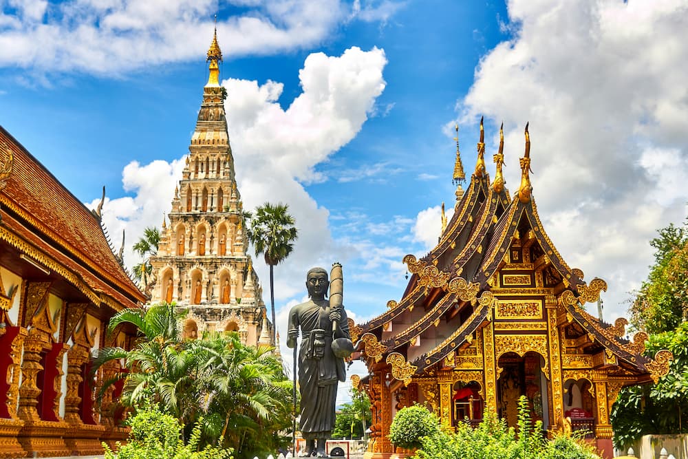 Statue de Bouddha devant un temple majestueux en Thaïlande